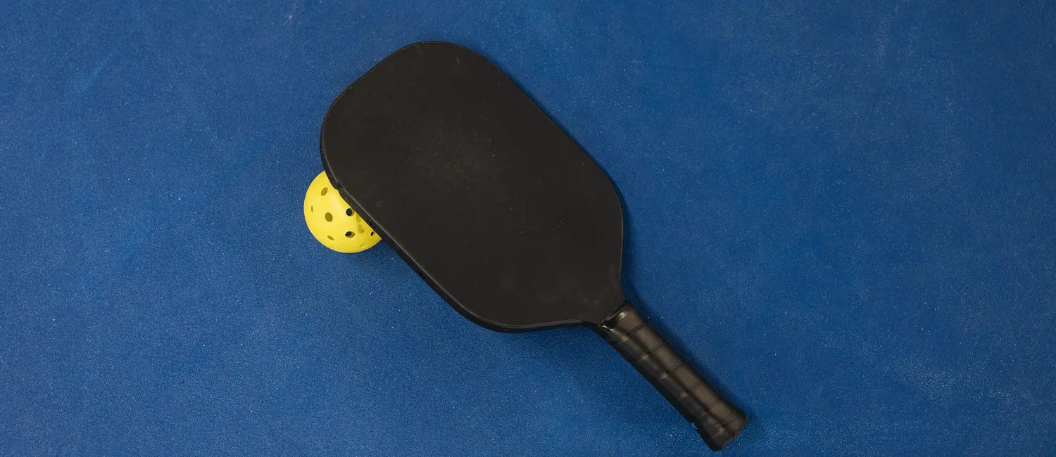 Pickleball paddle and ball on a blue court
